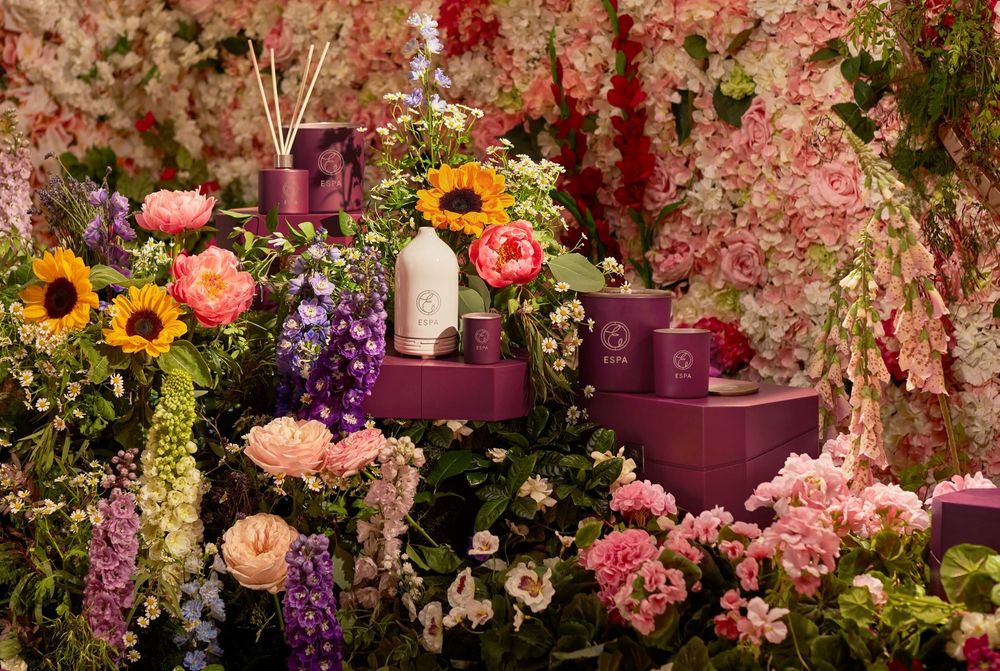 A selection of ESPA products set against a backdrop of flowers and floral arrangements