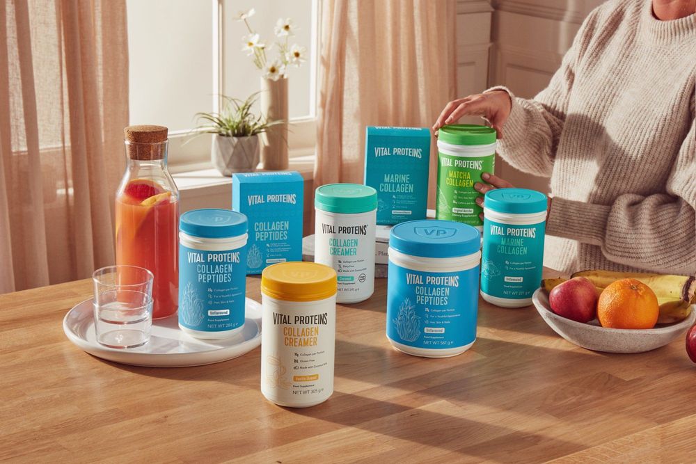Vital Proteins products on table with bowl of fruit and woman holding one of the products