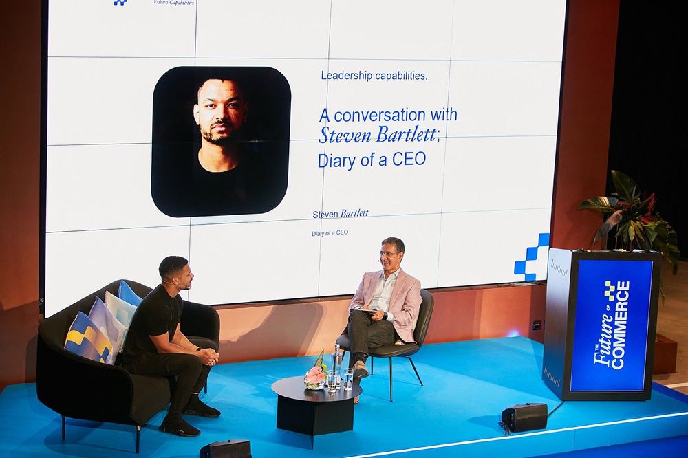 two men sat in front of a big screen talking