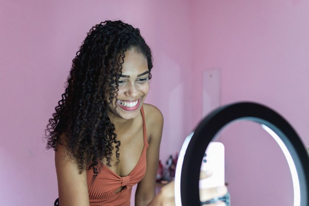 woman recording a video on a smartphone in front of a backlight