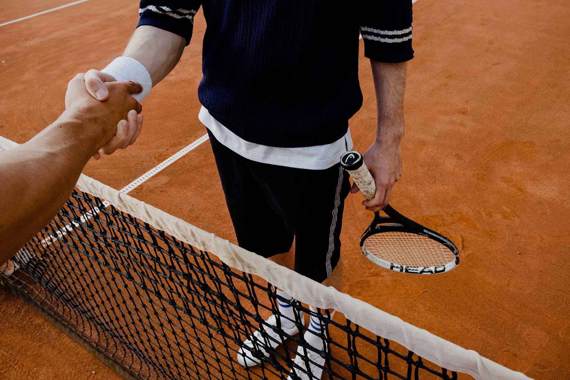 Tennis players shaking hands on court, representing SPF needs for prolonged outdoor matches.
