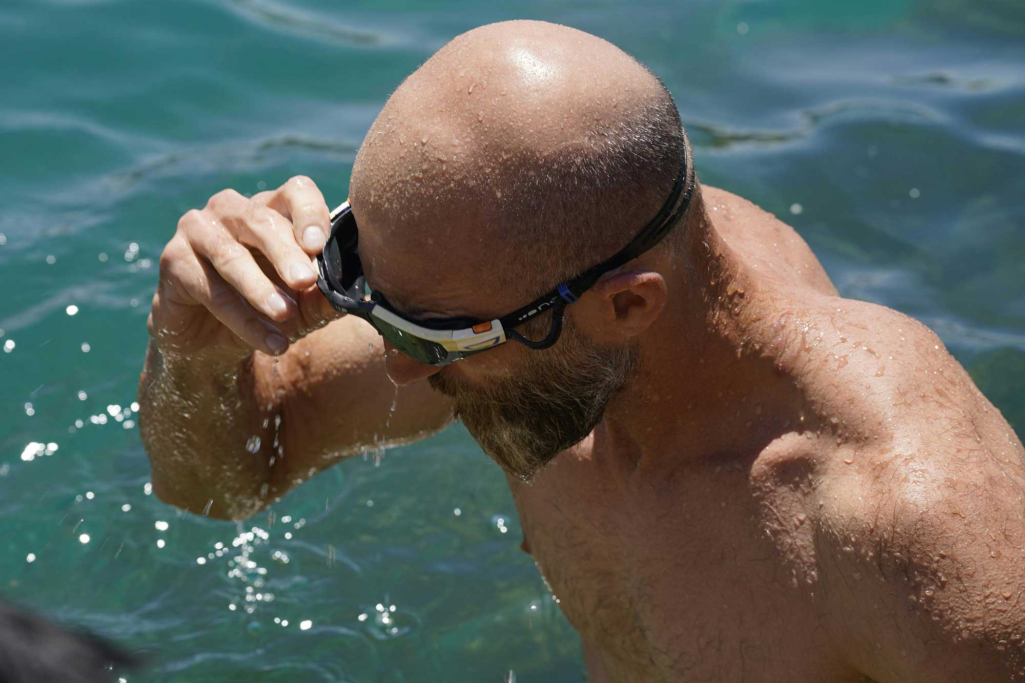 Bald man swimming outdoors, emphasising scalp vulnerability and targeted SPF protection.