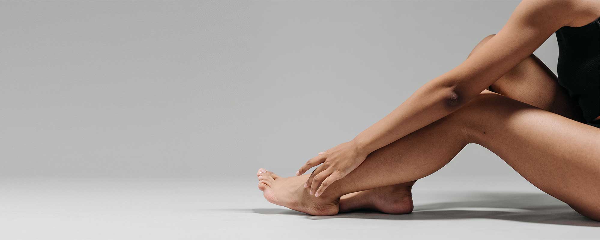Woman applying skincare to her leg, illustrating how facial skincare science is influencing advanced body care formulation and product development.