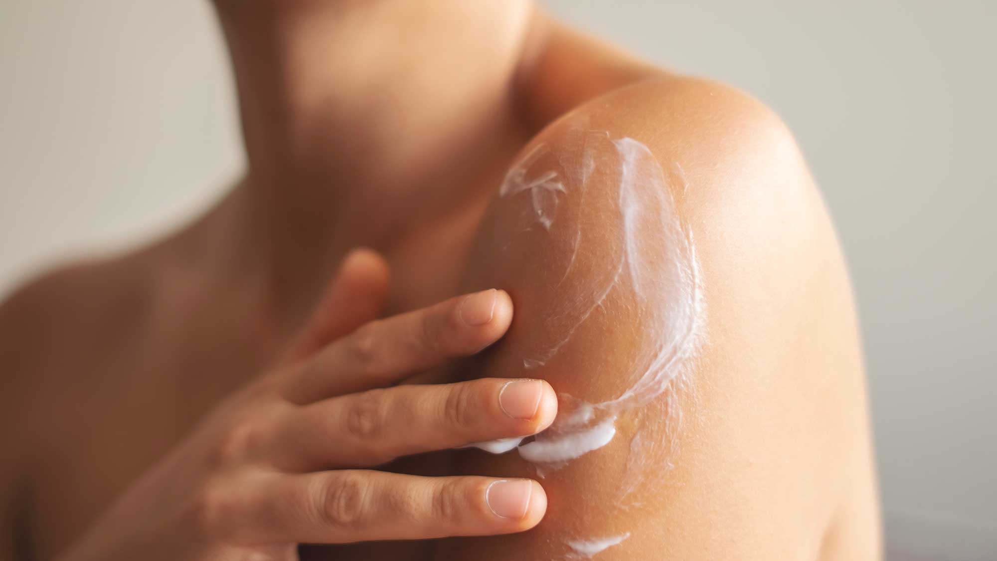 body moisturising cream being applied to the shoulder, illustrating bespoke body care textures and sensorial cosmetic formulation.