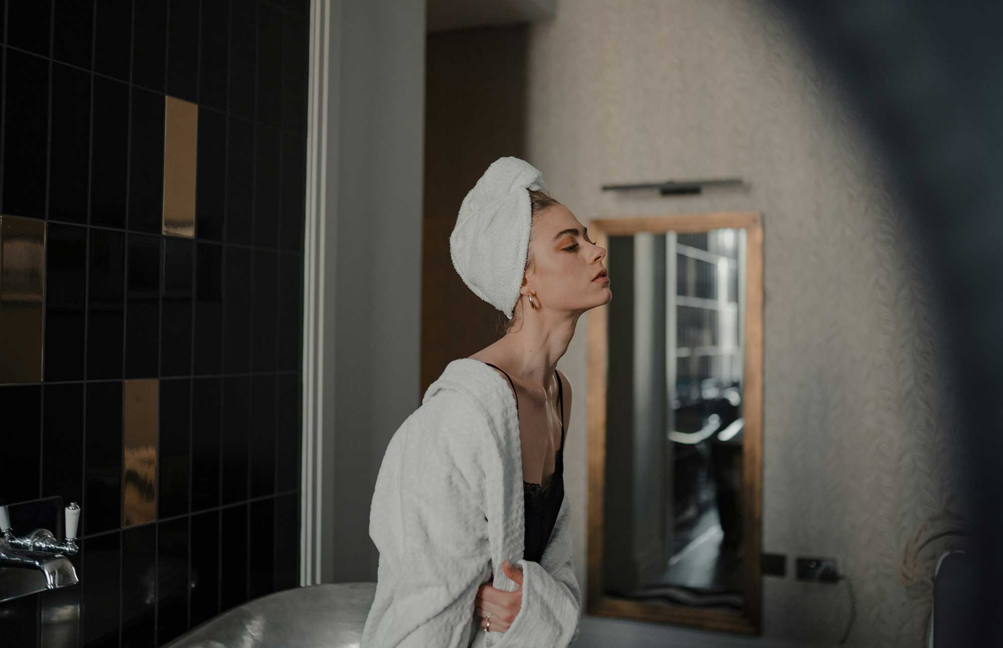 Woman in a bathrobe and towel illustrating premium body care, wellness rituals and sensorial skincare product development opportunities.