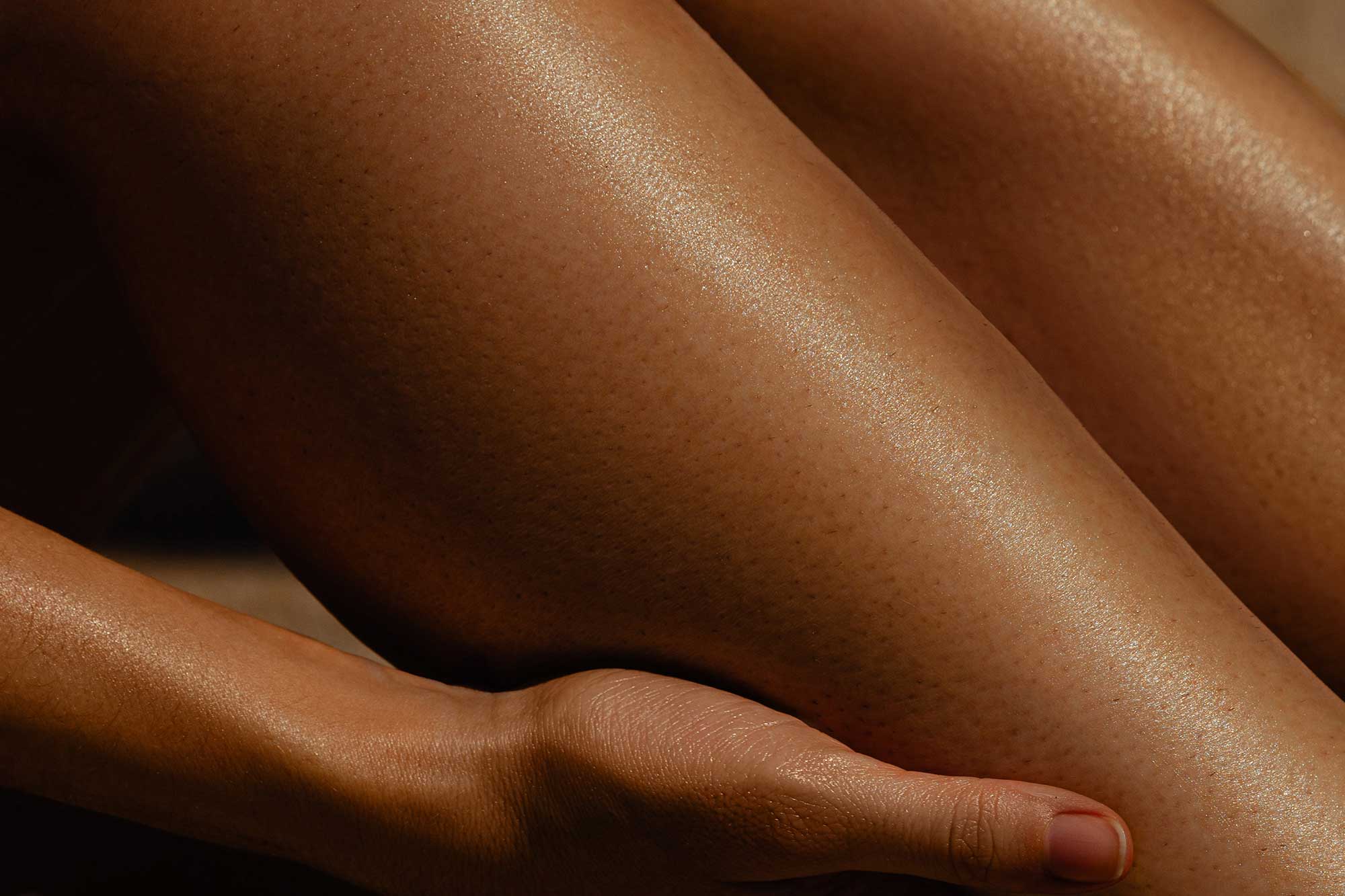 Hand touching moisturised skin, illustrating absorption, after-feel and sensory performance considerations in body care formulation