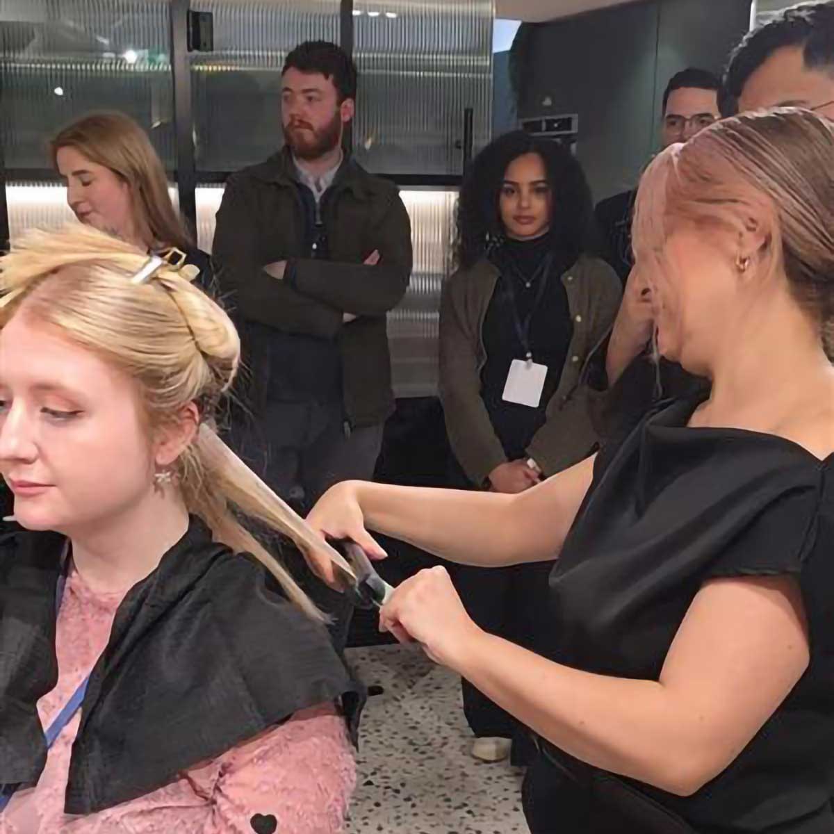 Haircare expert demonstrating a styling and assessment technique on a model while THG LABS observe at the Chemyunion Haircare Innovation Event in London.