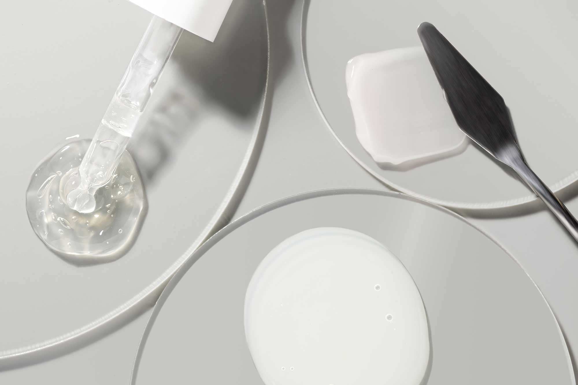 Cosmetic serum and cream textures in laboratory sample dishes, illustrating dermocosmetic formulation and skincare-inspired body care development.