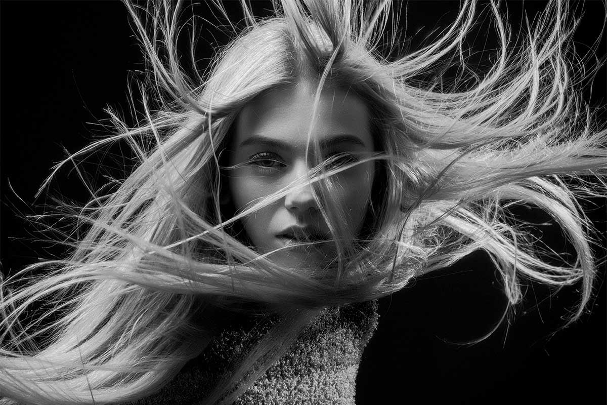 Model with wind-swept hair representing haircare innovation and product development expertise at THG LABS beauty manufacturing facilities