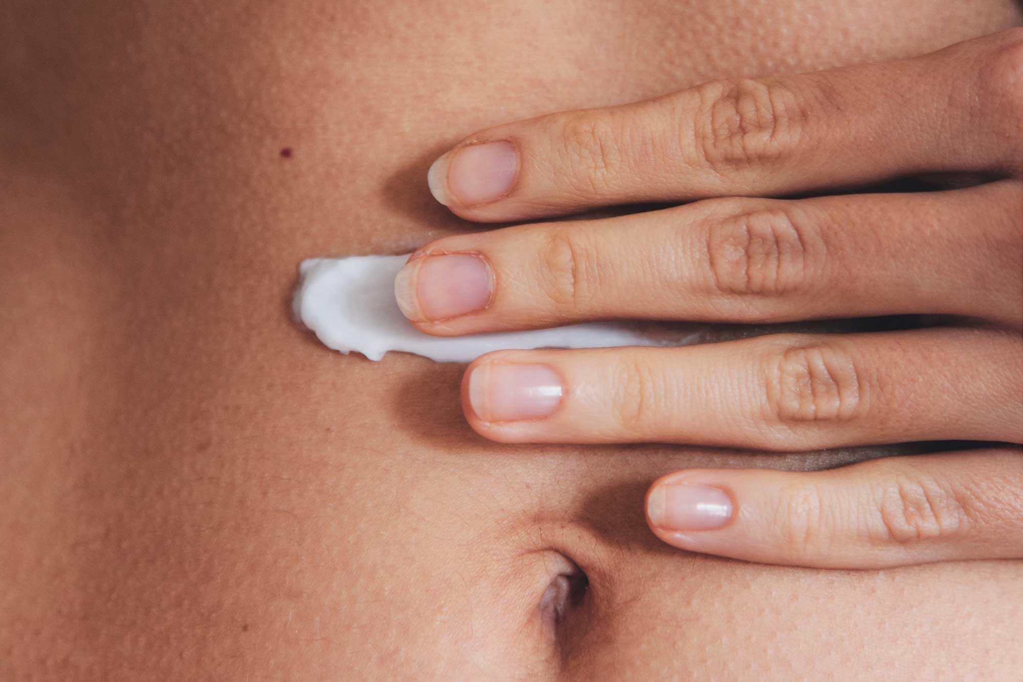 Body cream being applied to the abdomen, illustrating targeted skincare benefits, body moisturiser formulation and performance-led product development.