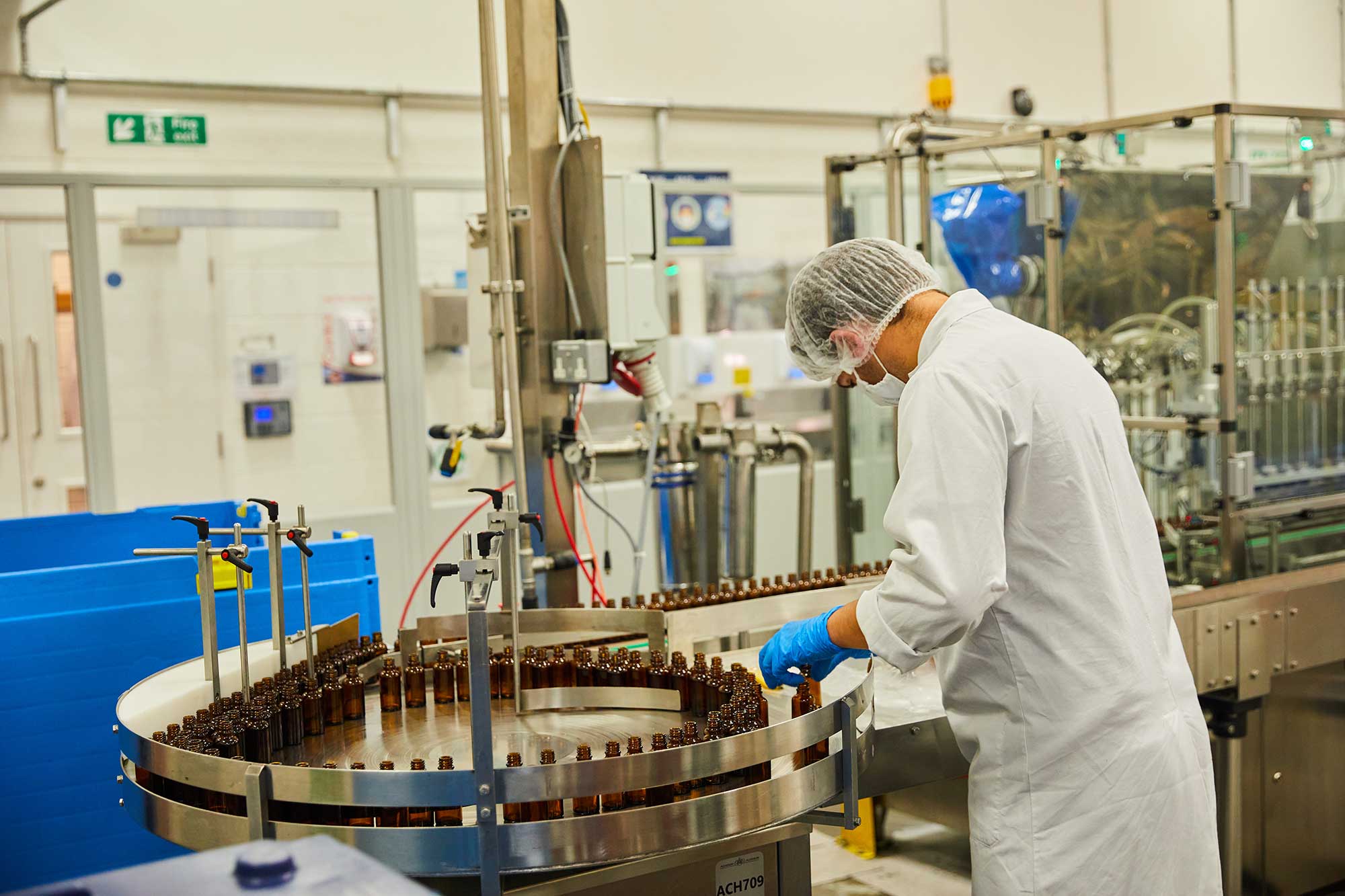 Production operator inspecting bottles on a skincare filling line inside THG LABS UK cosmetics factory, showcasing end-to-end product development and quality control in beauty manufacturing.