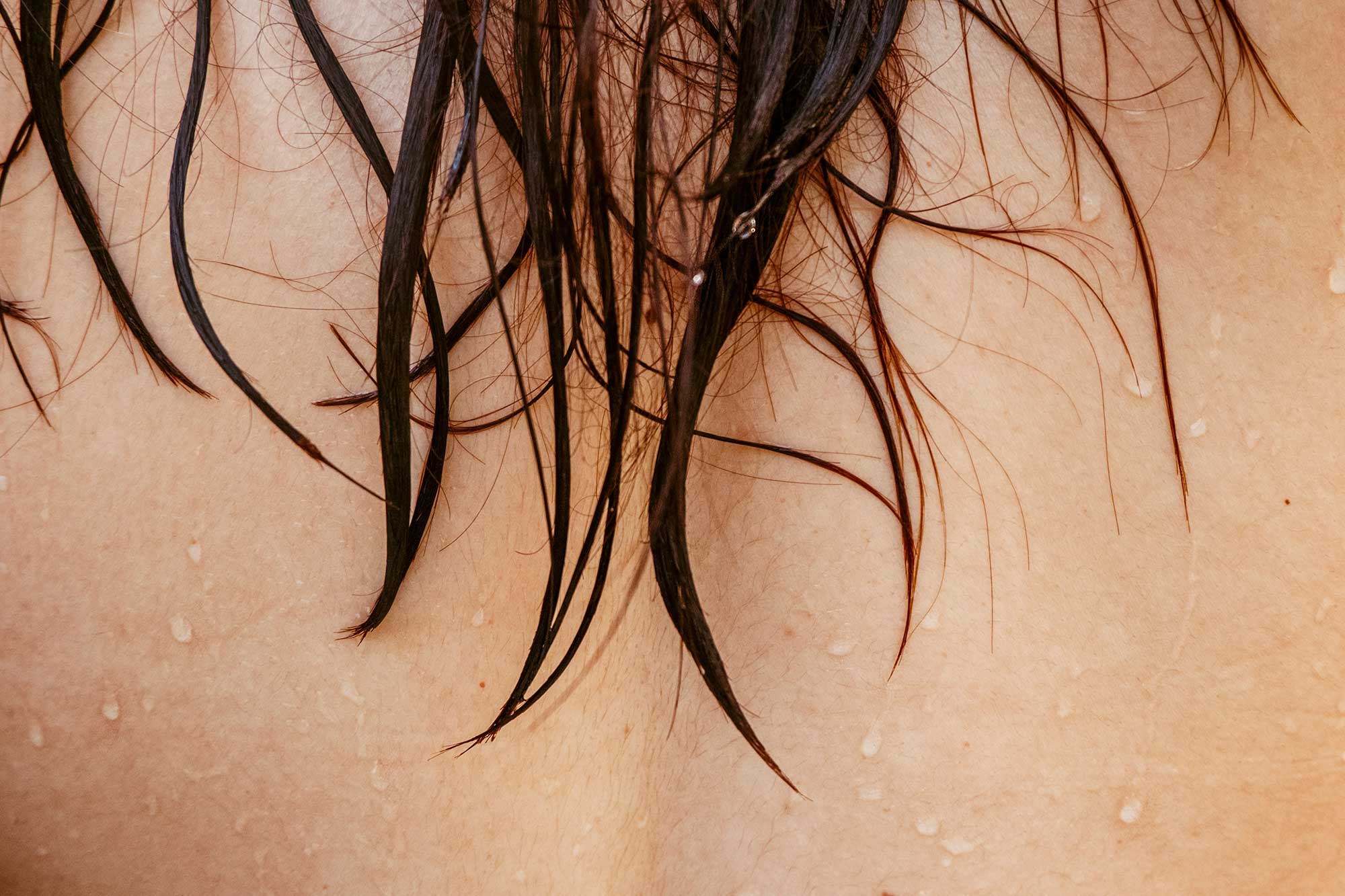 Close-up of wet hair strands on skin illustrating hydration, conditioning performance and advanced haircare formulation and manufacturing expertise